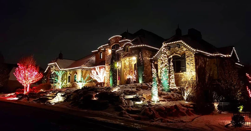 Holiday accent lighting on trees and evergreens with warm roofline lights